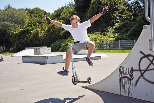 Boy rides scooter in a pipe at a skate park
