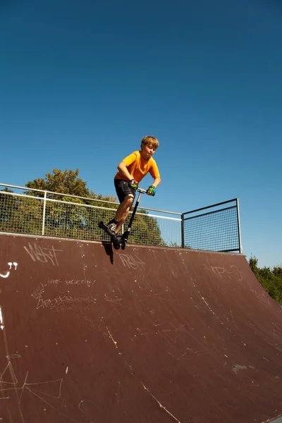 Chłopiec skacze ze skutera na kręgosłup w skate parku i — Zdjęcie stockowe