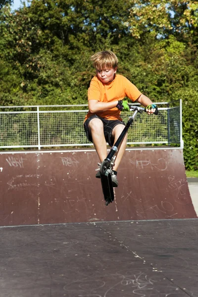 Boy rides scooter at the skate park — Stock Photo, Image