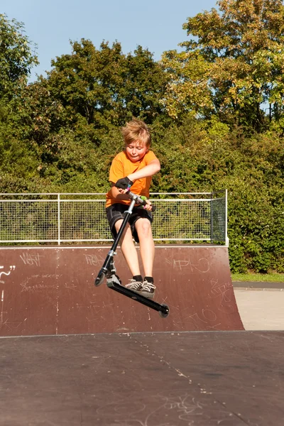 Boy rides scooter at the skate park — Stock Photo, Image
