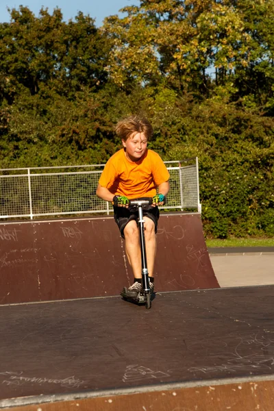 Fiú túrák robogó a skate park — Stock Fotó