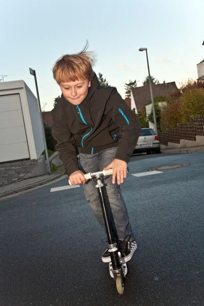 Ładny chłopak scooting z jego skuter — Zdjęcie stockowe