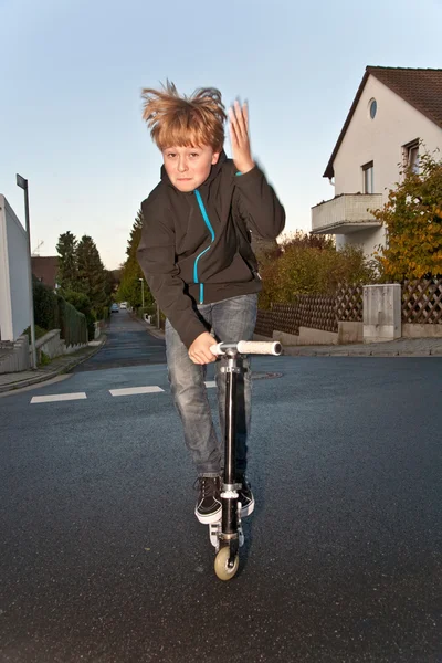 Söt pojke scooting med sin skoter — Stockfoto