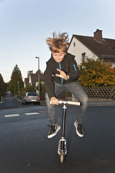 Ładny chłopak scooting z jego skuter — Zdjęcie stockowe