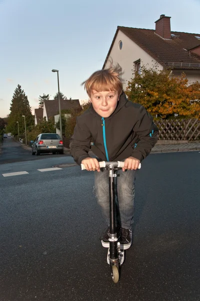 Söt pojke scooting med sin skoter — Stockfoto