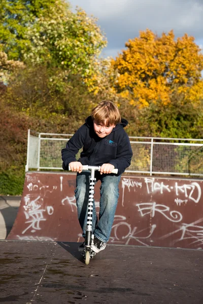 Rapaz bonito scooting com sua scooter — Fotografia de Stock