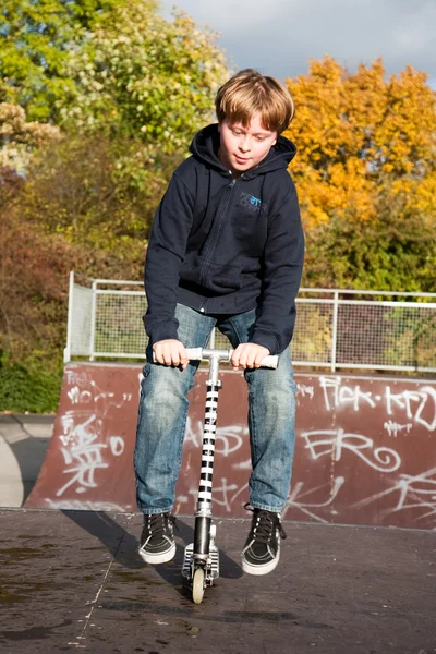 त्याच्या स्कूटरसह सुंदर मुलगा स्कूटिंग — स्टॉक फोटो, इमेज