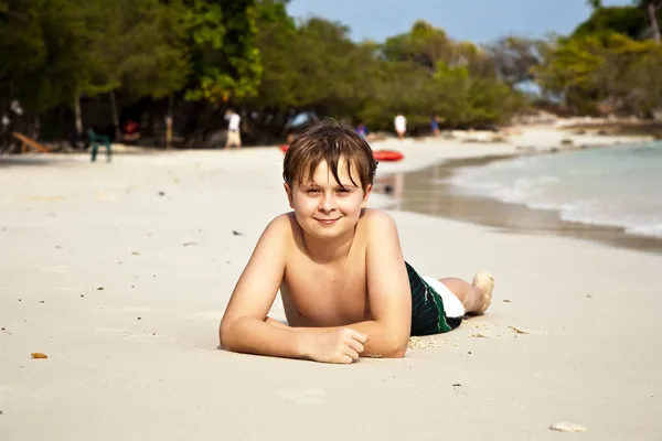 Szczęśliwy chłopiec leżąc na plaży — Zdjęcie stockowe