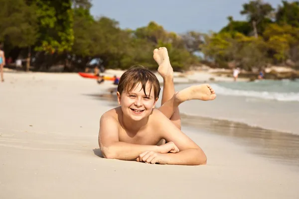 Счастливый мальчик лежит на пляже — стоковое фото