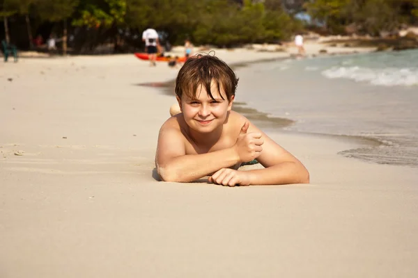 Szczęśliwy chłopiec leżąc na plaży — Zdjęcie stockowe