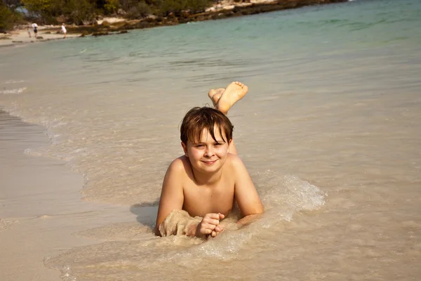 Rapaz feliz deitado na praia — Fotografia de Stock