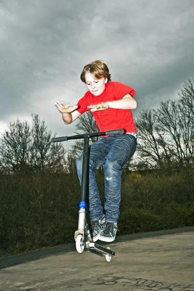 Chico va en el aire con un scooter — Foto de Stock