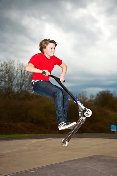 Мальчику нравится кататься на скутере в скейт-парке — стоковое фото