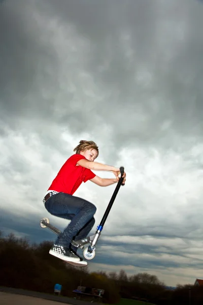 Menino indo para o ar com uma scooter — Fotografia de Stock