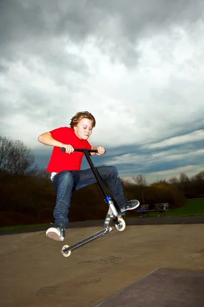 Мальчик спускается в воздух на скутере — стоковое фото