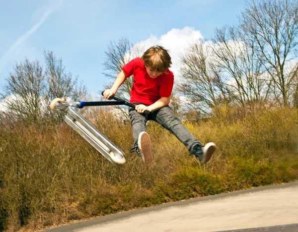 Menino indo para o ar com uma scooter — Fotografia de Stock