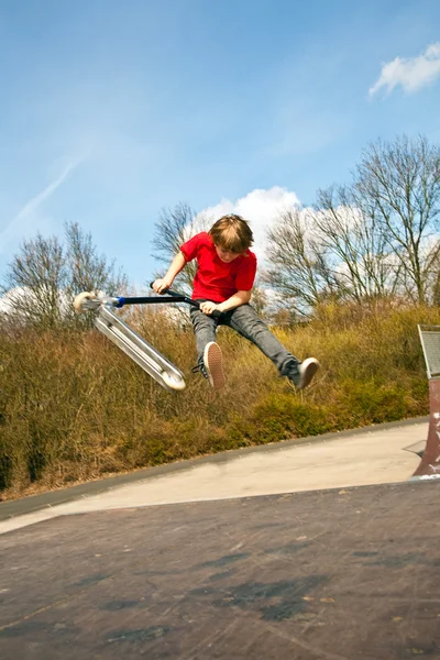 Мальчик спускается в воздух на скутере — стоковое фото