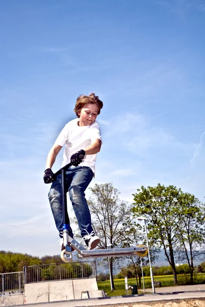 Chlapec jde vzduchem s skútr — Stock fotografie