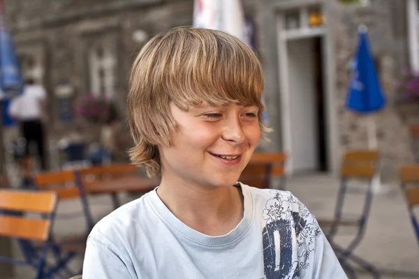 Retrato de menino sorridente feliz sentado em um restaurante ao ar livre — Fotografia de Stock