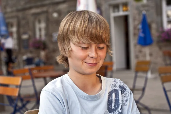 Porträt eines glücklich lächelnden Jungen, der in einem Restaurant im Freien sitzt — Stockfoto