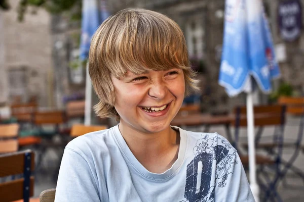 Portret szczęśliwy uśmiechający się chłopak siedzi w restaurację na świeżym powietrzu — Zdjęcie stockowe
