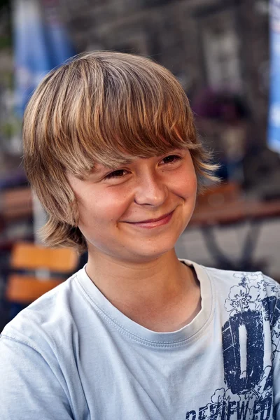 Porträt eines glücklich lächelnden Jungen, der in einem Restaurant im Freien sitzt — Stockfoto