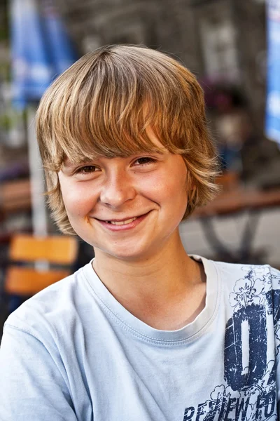 Portrait of happy smiling boy sitting in an outdoor restaurant — Stock Photo, Image