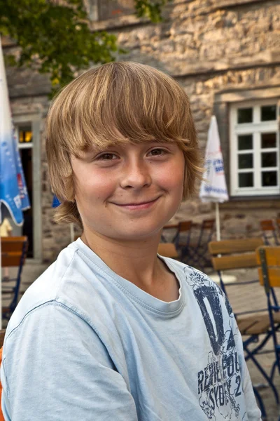 Porträtt av glada leende pojke sitter i en utomhus restaurang — Stockfoto