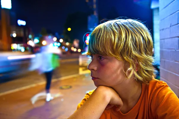 Cute boy smiles tired while sitting outside by night — Stock Photo, Image