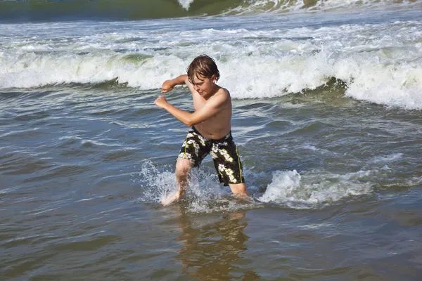 Młody chłopak działa w wodzie na plaży — Zdjęcie stockowe