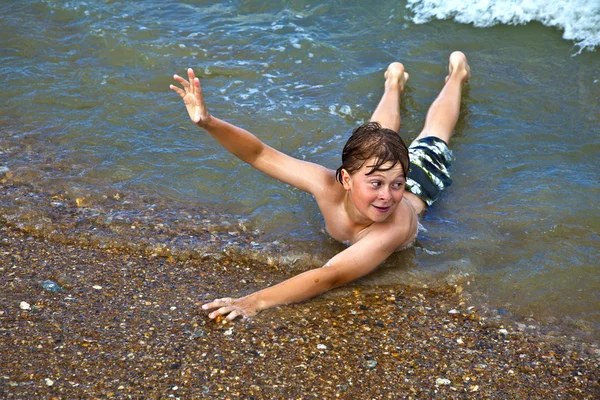 Menino deitado na água dá sinal de mão — Fotografia de Stock