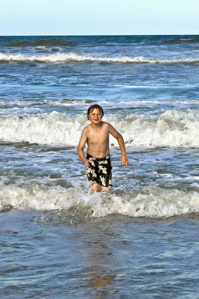 Menino correndo pela água na praia — Fotografia de Stock
