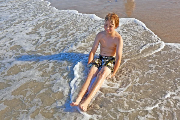Мальчик лежит на пляже и наслаждается океаном — стоковое фото