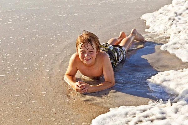 Fiú feküdt a tengerparton, és élvezi az óceán — Stock Fotó