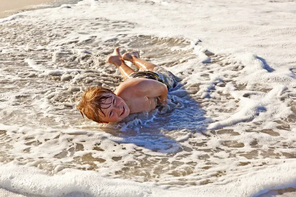 Niño acostado en la playa y disfrutando del océano —  Fotos de Stock