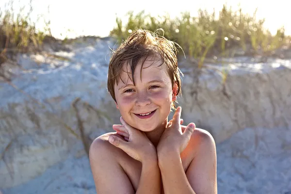 Молодой счастливый улыбчивый мальчик на пляже — стоковое фото