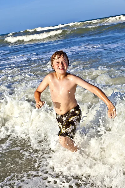 Jeune garçon jouit des vagues de la mer bleue — Photo