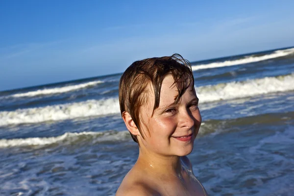 Молодий хлопчик насолоджується хвилями блакитного моря — стокове фото