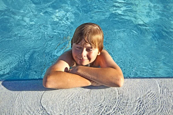 Criança descansa em seu cotovelo na borda da piscina — Fotografia de Stock