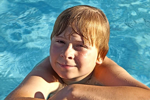 Kind rest op zijn elleboog op de rand van het zwembad — Stockfoto
