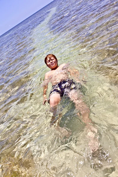 Roztomilý chlapec má zábavu v křišťálově čistý oceán — Stock fotografie