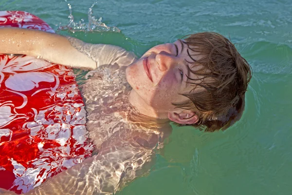 Menino em um ringue de natação se diverte na ocea — Fotografia de Stock