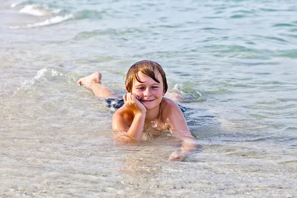Chłopak cieszy się leżąc na plaży w surf — Zdjęcie stockowe