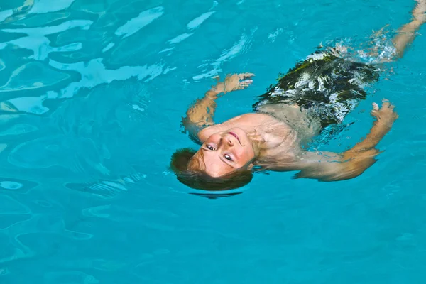 Menino gosta de nadar na piscina exterior — Fotografia de Stock