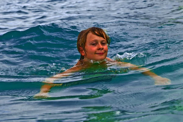 Rapaz está nadando no oceano — Fotografia de Stock
