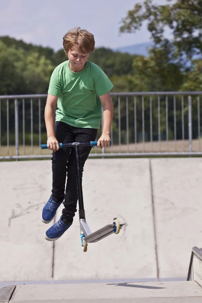 Jonge jongen gaat vliegen met zijn scooter — Stockfoto