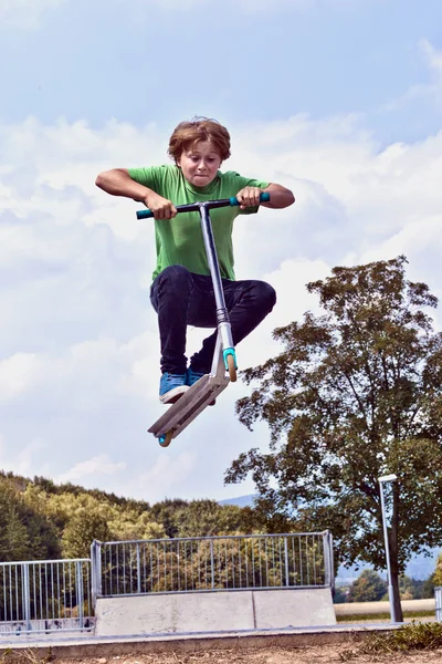 Мальчик летит в воздух на скутере. — стоковое фото