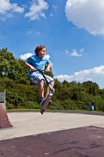 Menino indo no ar com sua scooter — Fotografia de Stock