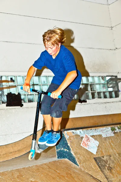 Menino vai para o ar com sua scooter — Fotografia de Stock