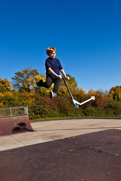 Dítě se ve vzduchu s jeho skútr — Stock fotografie